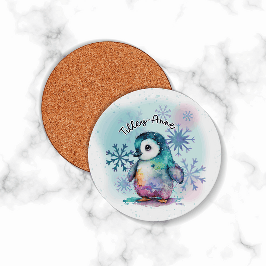 Coaster with a penguin design and cork back on a marble surface